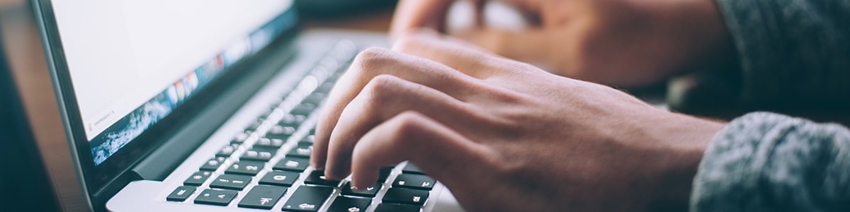 Hands typing on a laptop